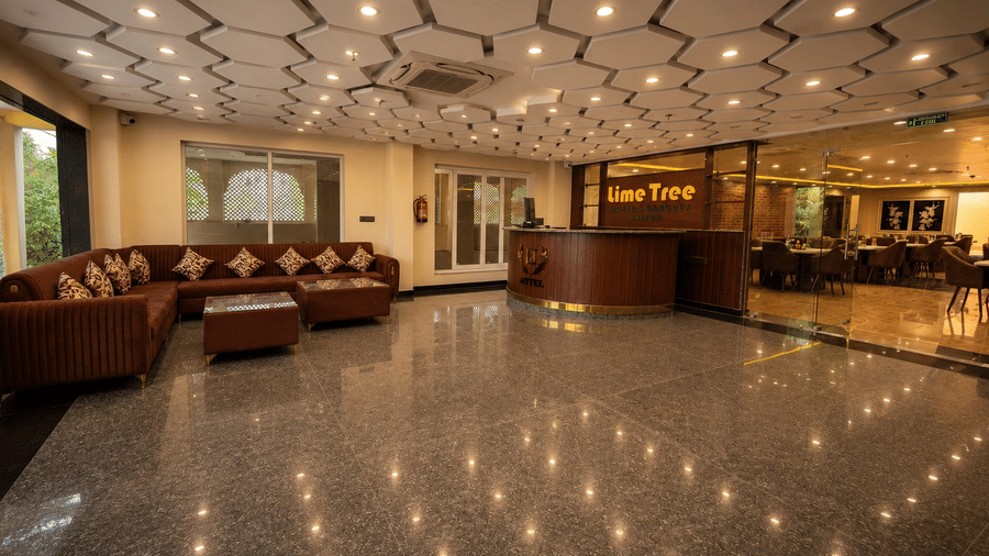 A wide view of the reception lobby at Lime Tree Hotel & Banquet, Jaipur, showing the seating area, reception desk, and textured ceiling.