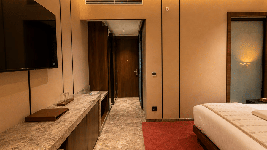 Loom room interior displaying a wall-mounted TV, long wooden work desk console, and hallway entry.