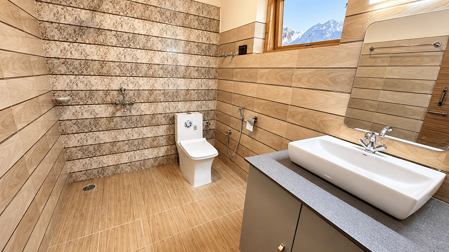 Bathroom with a tiled wall, glass shower enclosure, white washbasin, mirror and wooden-framed window.