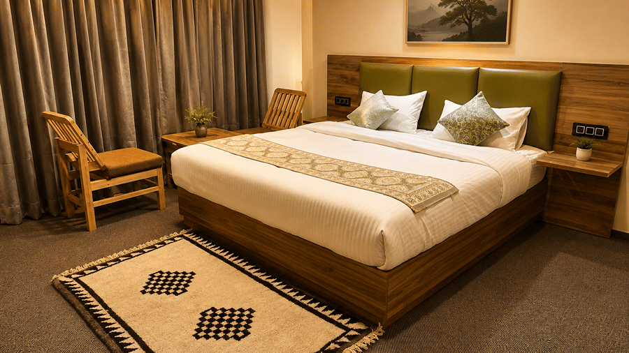 Bedroom with a queen-size bed, wooden headboard, bedside tables, armchair, curtains and patterned floor rug.