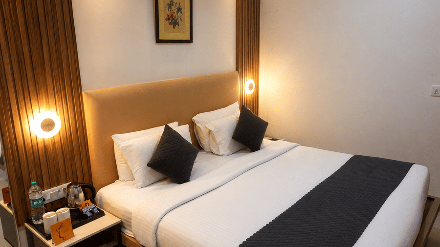 Premium Room at TGI Apple Inn, Ajmer Road, Jaipur featuring a bed, lamps on the wall, artwork, and a bedside table.