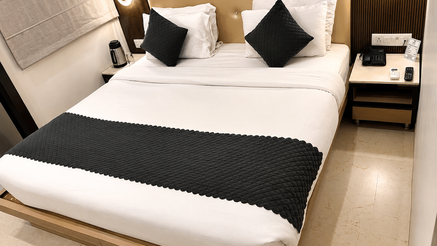 Studio Room at TGI Apple Inn, Ajmer Road, Jaipur featuring a bed with pillows, lamps, and a bedside table with a telephone.