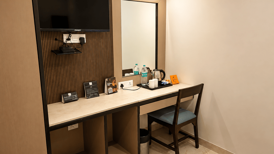 Studio Room at TGI Apple Inn, Ajmer Road, Jaipur featuring a desk with a chair, television, mirror, and tea-making facilities.