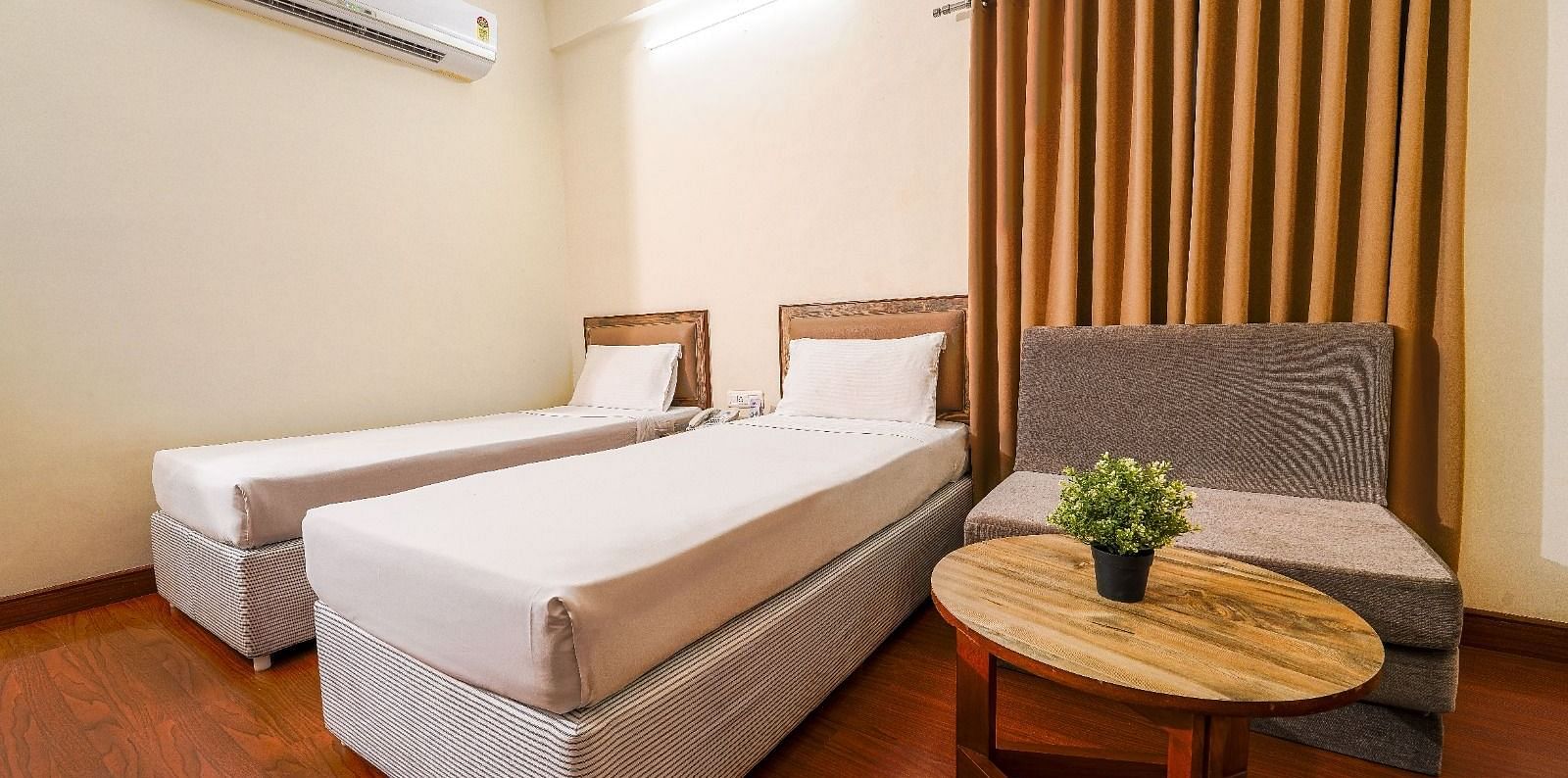 Hotel room with two single beds, a comfortable couch, and a coffee table in Hyderabad near Ramoji Film City.