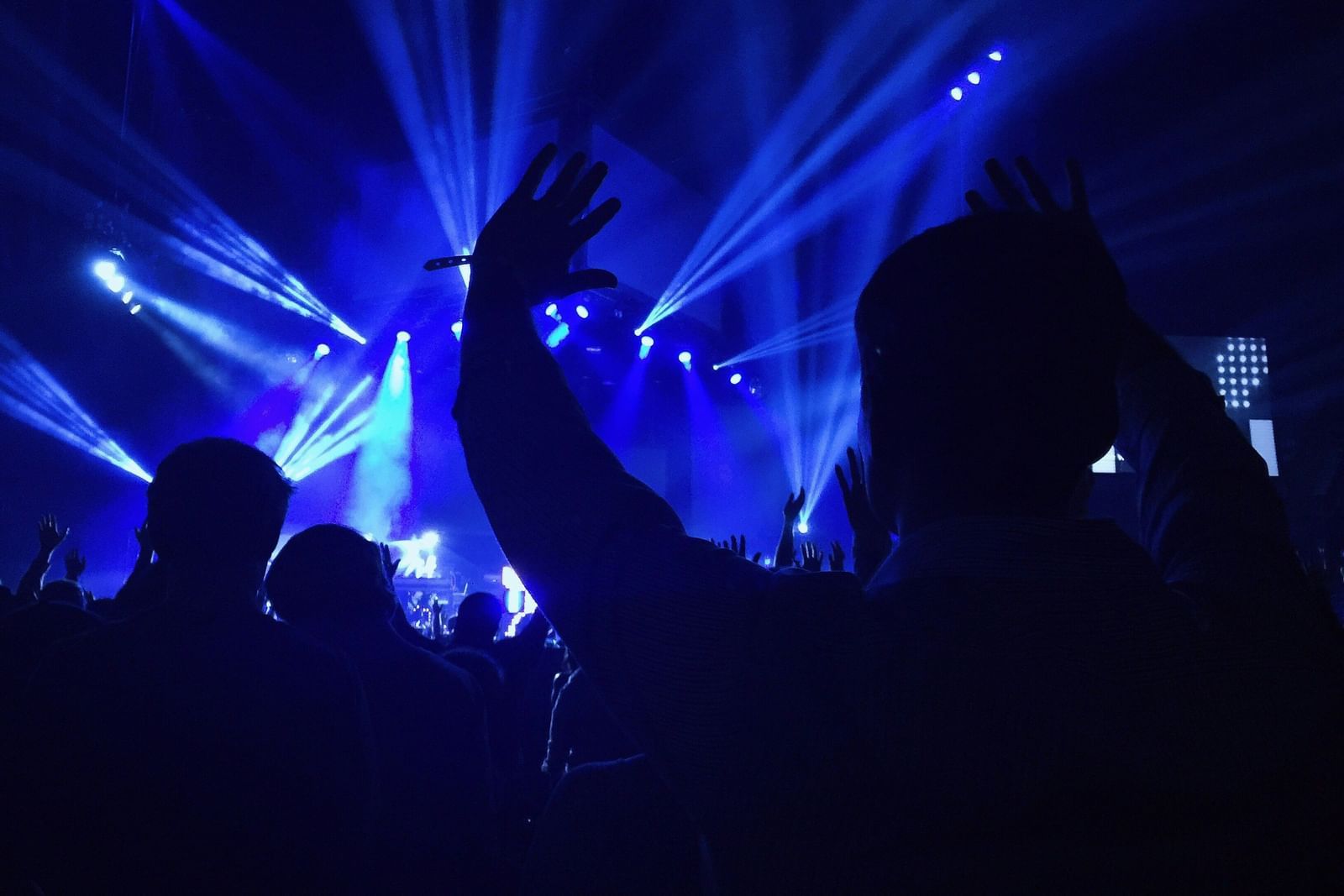 an image of a crowd enjoying DJ night illuminating blue light.