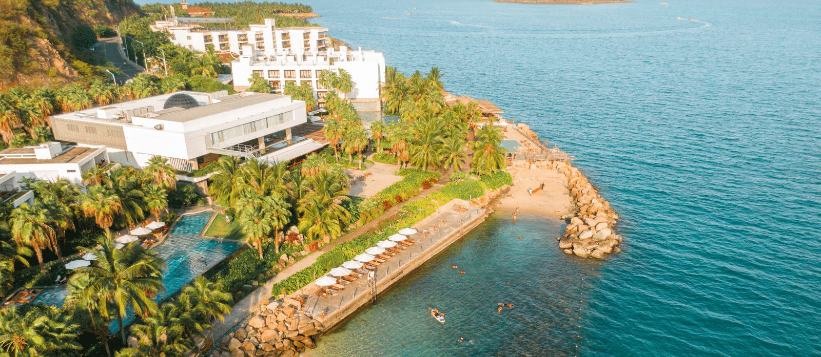 Aerial view of different sections in Alibu Resort, Vietnam amidst the palm trees, also featuring private beaches leading to the sea. 