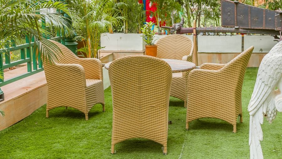 An image of a coffee table with four chairs placed around it in a rooftop  lawn