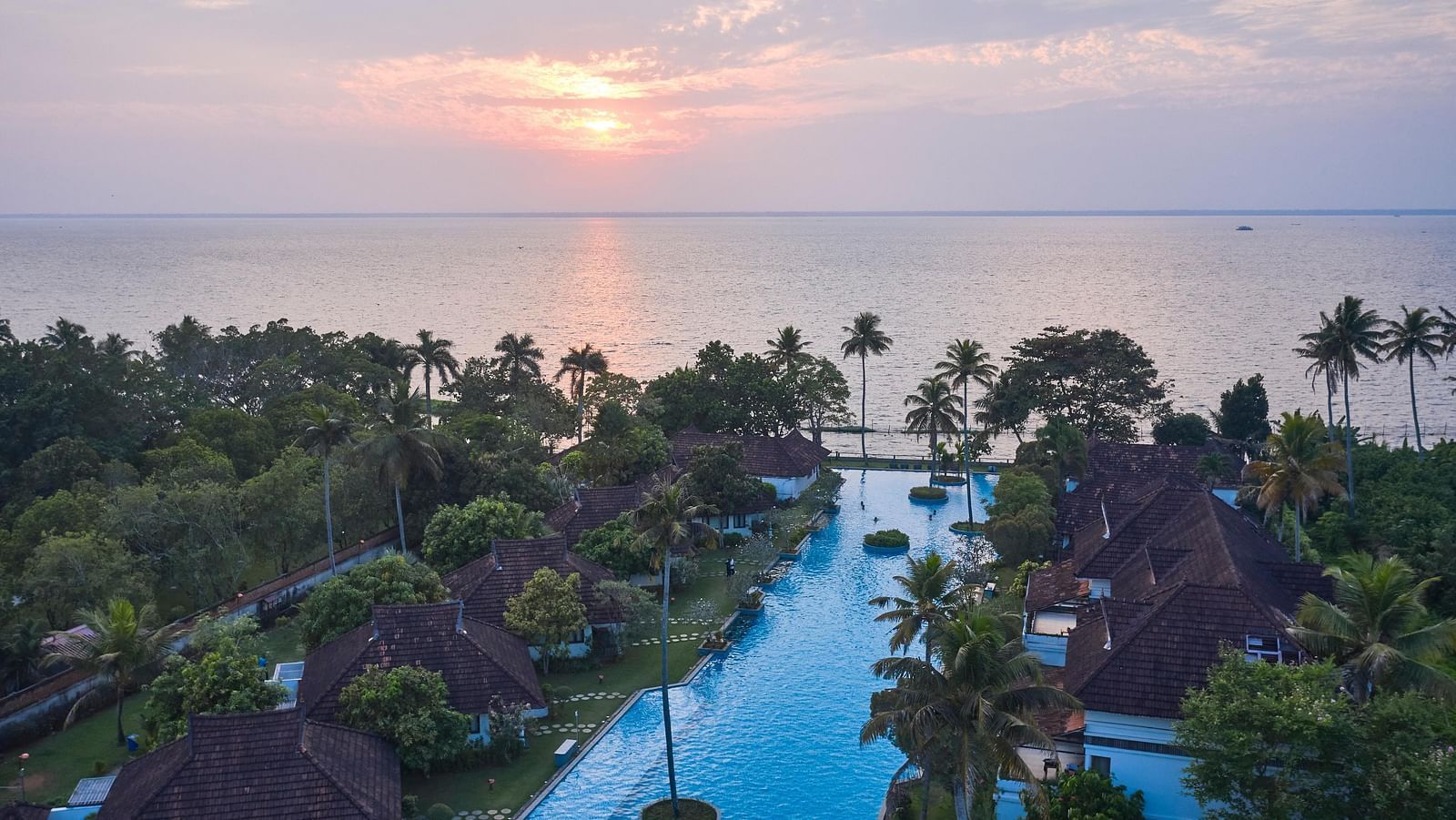 Aerial view of Rhythm Kumarakom with a swimming pool covered by coconut trees.