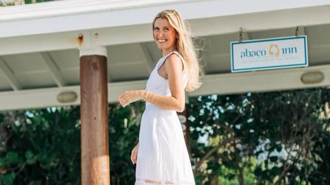 Bride in wedding dress stands under a canopy near greenery at Abaco Inn.