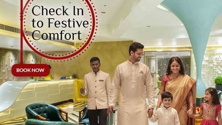 A family dressed in festive attire checks into The Citi Residenci hotel lobby, greeted warmly by staff for a joyful Durga Puja stay.