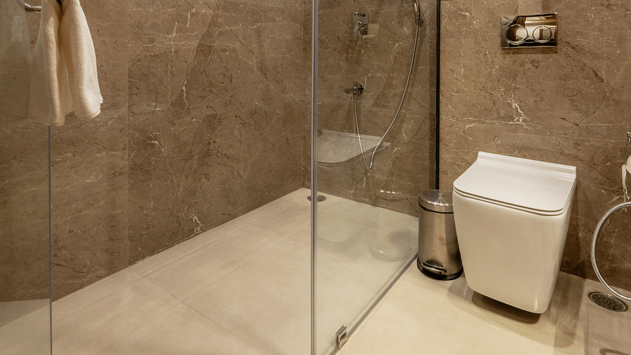 A washroom with the shower area, a toilet seat, and other toiletries - Brij Castle, Jaipur