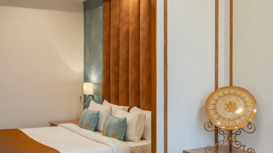 Corner of a stylish bedroom with a bed, vanity table, and mirror, featuring gold trim and a velvet headboard at Hotel Hukam's Lalit Mahal.