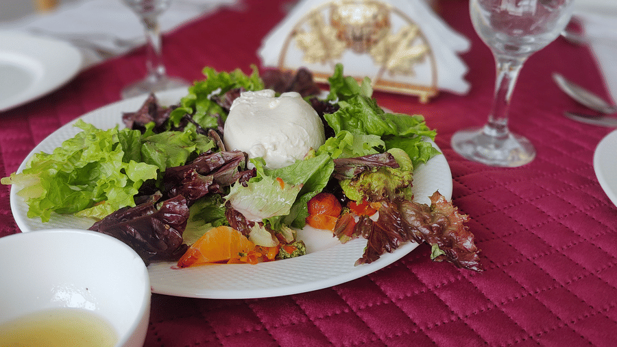 A close-up of a fresh green salad served on a white plate over a textured red table runner at Indus Serenity Retreat.