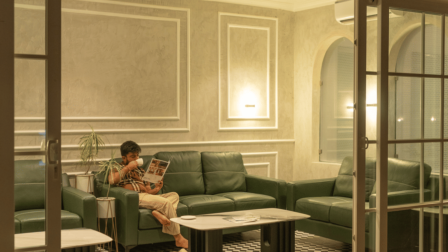 Night-time view of the crimson cafe interior with a person seated, featuring warm lighting and a checkered floor at Hotel Hukam's Lalit Mahal.