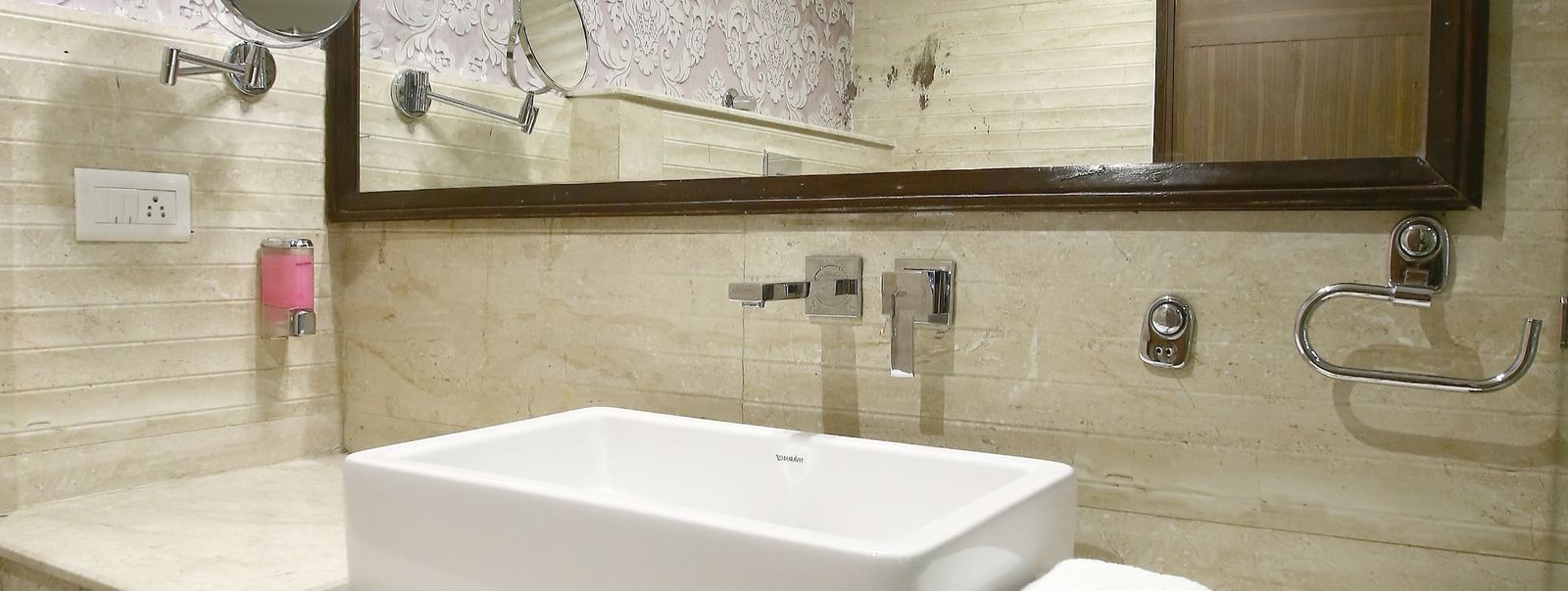 a well lit bathroom with a huge mirror, sink, towel and cabinet  