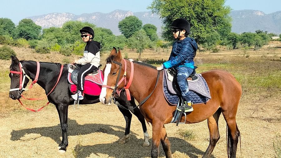 An image of two kids sitting on two separate horses - Utsav Camp Sariska