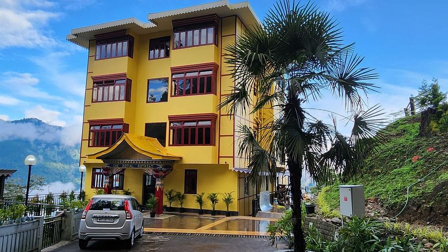 A long shot of the facade of our hotel in Gangtok set against a backdrop of blue sky, surrounded by greenery |  Voyage The Royal Retreat