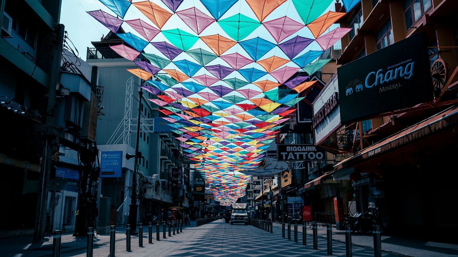 An overview of an empty Khao San Road with kites sticked together as a sun shade.