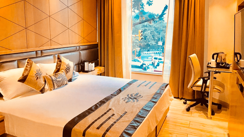 A Superior Room at JRD Pride - Business Hotel featuring a well-made bed, an accent wall, a work desk, and a large glass window. 