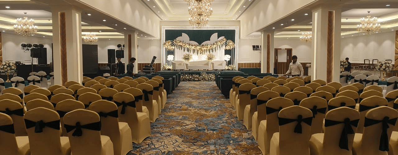 Brij Eternity, Vrindava |  A spacious, opulent banquet hall with rows of chairs arranged for a wedding function.