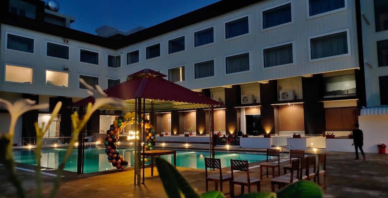 An evening view of a resort building with illuminated windows surrounding a swimming pool - Bamboo Saa Mulberry Resort, Pushkar