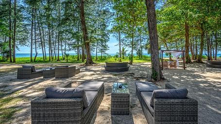 A well arranged dining area amidst tall green trees and a clear blue sky - Maikhao Dream Villa Resort & Spa, Phuket