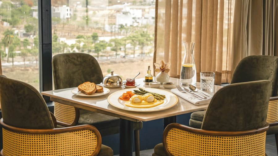 A served breakfast plate, toasted bread, a water carafe, and glasses on a table at Pride Plaza Indore.