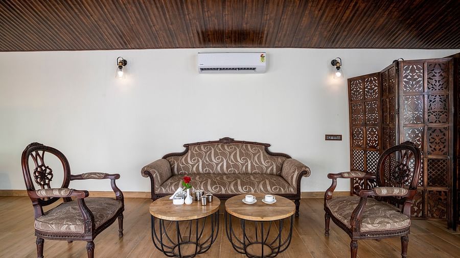A living area with two chairs and a sofa placed in front of coffee tables - Stone Wood Nature Resort, Gokarna