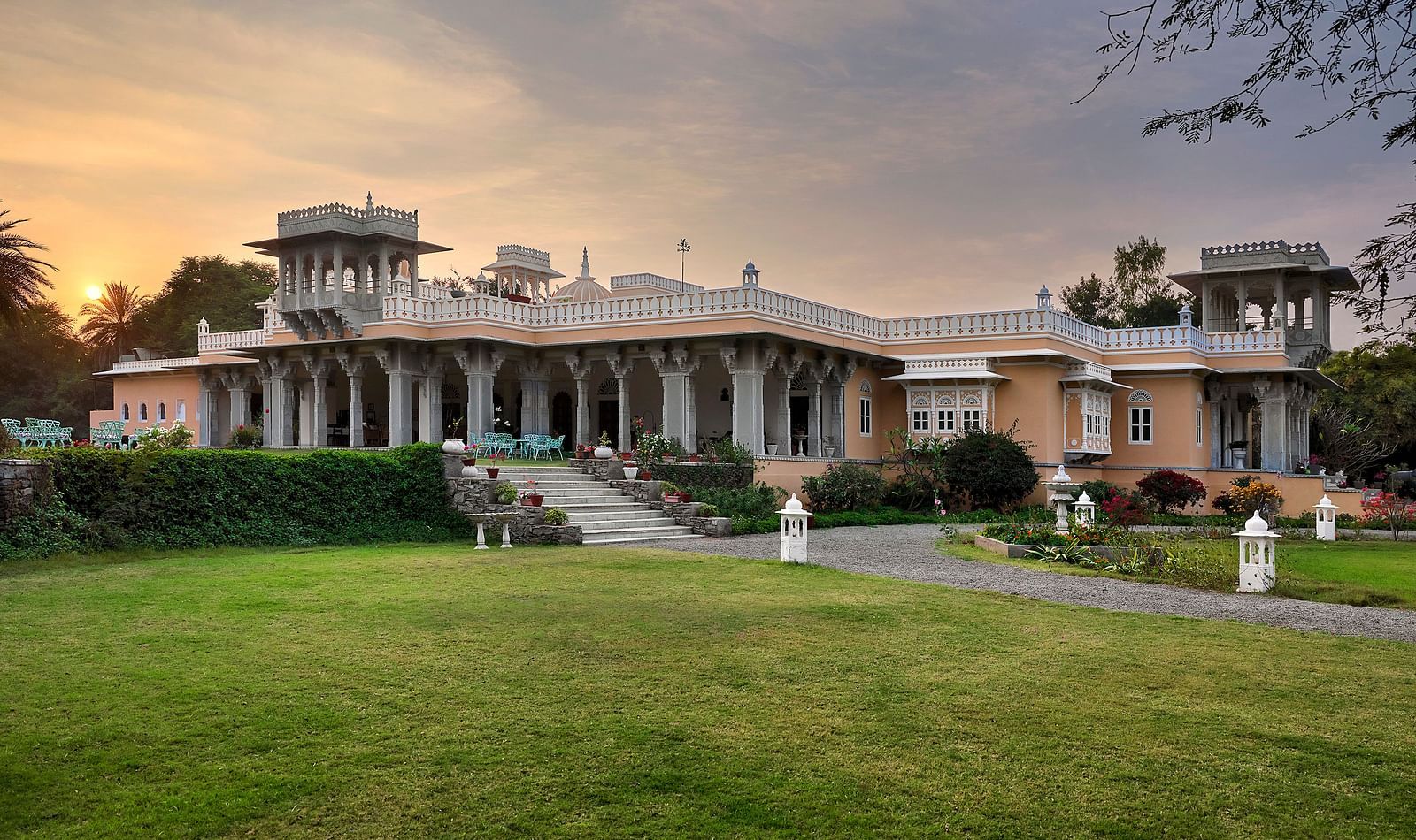 facade image of dev shree, deogarh with a beautiful lawn in the foreground and a picturesque sunset in the background