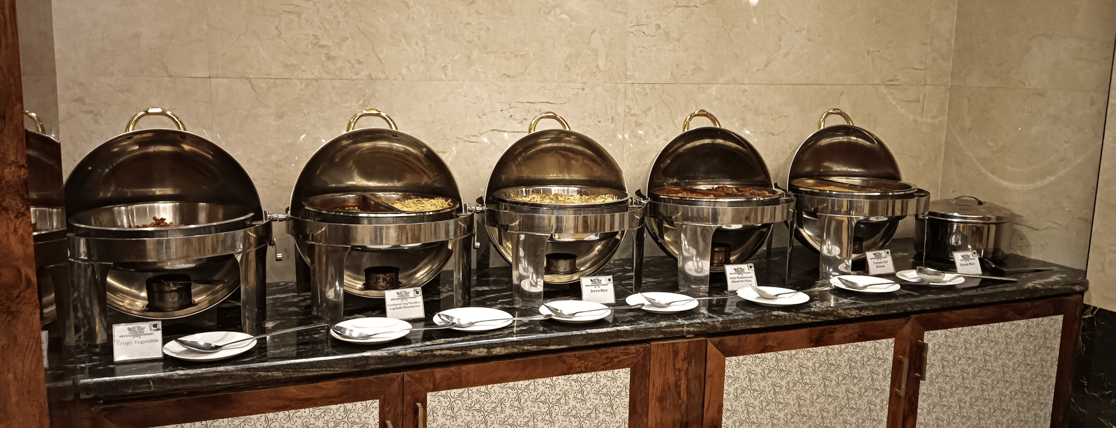 A buffet counter with gleaming chafing dishes arranged for a delectable multi-cuisine dining spread - Benzz Park, Kodaikanal