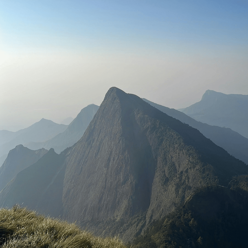 Mountain peak rising through misty valleys beneath a clear blue sky during bright daylight