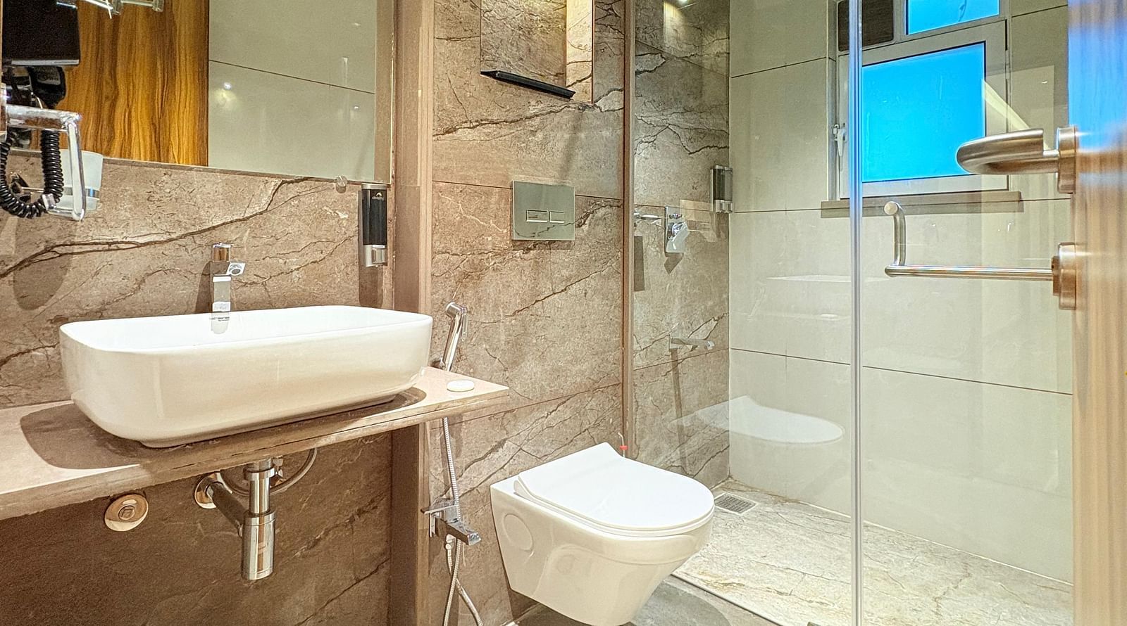 Bathroom featuring a wash basin, shower space, and mirror at Hotel Mumbai House, Vashi.