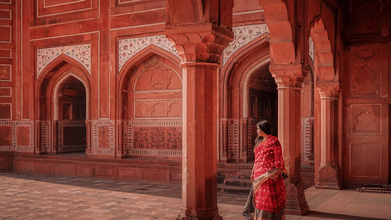 A woman in a saree walking through the corridors of a historic monument