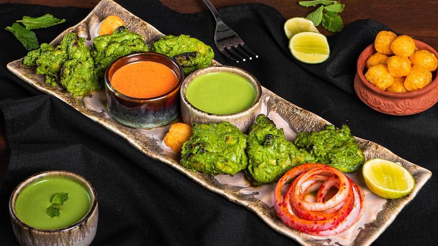Plated Indian thali with chapati, rice, sweets, and condiments on a black serving board.