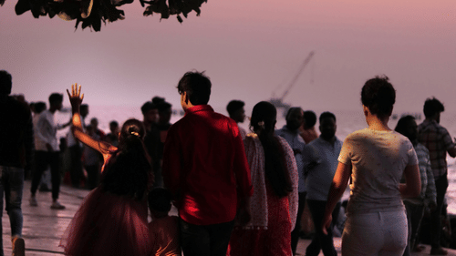 a group of people walking on the beach with a tree above them and water on their feet