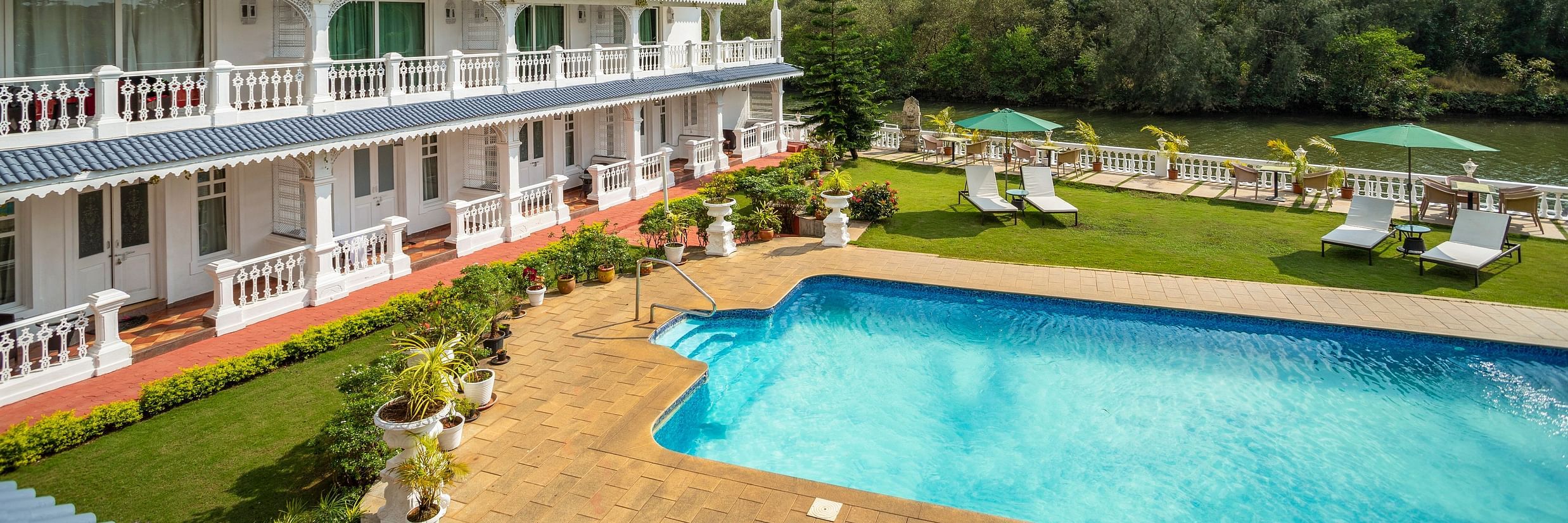 The facade of the hotel alongside the pool - Stone Wood Riverfront Resort, Siolim