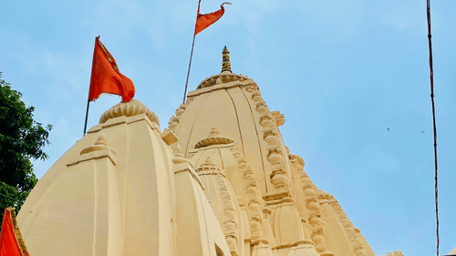 An image of a temple with red flags fluttering in the wind, set against a clear sky.