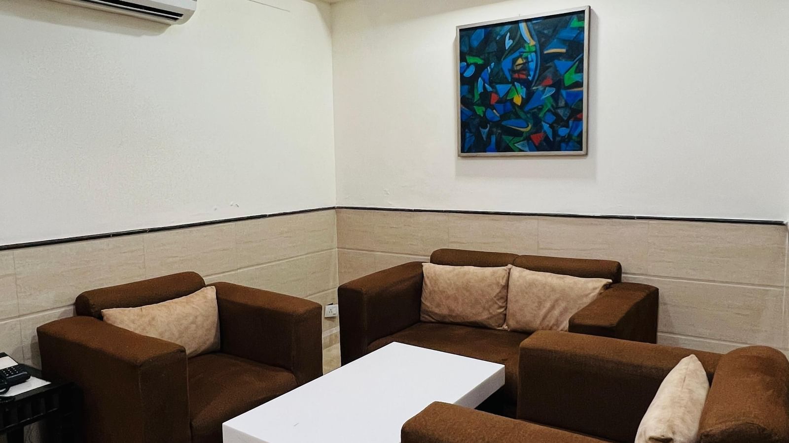 A luxurious hotel suite with a large bed, dark wood furniture, and modern amenities, offering a sophisticated stay. | Suite | Hotel Aadhar
