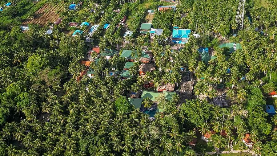 A scenic aerial shot of a tropical coastline, with dense greenery and a tranquil beach. The crystal-clear waters stretch along the shoreline, highlighting the serene environment - Coral Reef Resort & Spa, Havelock