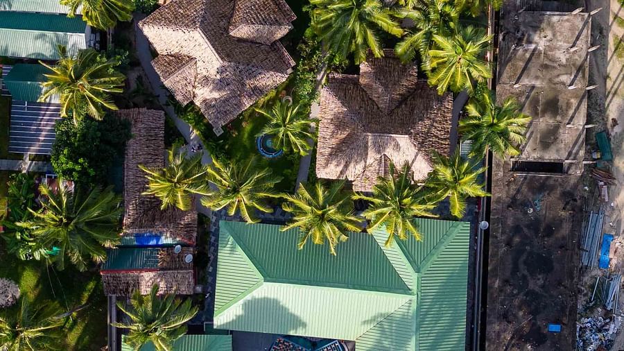 A panoramic view of the resort area, surrounded by trees and offering a clear view of the beach and the ocean. The wooden buildings are nestled amidst lush greenery - Coral Reef Resort & Spa, Havelock