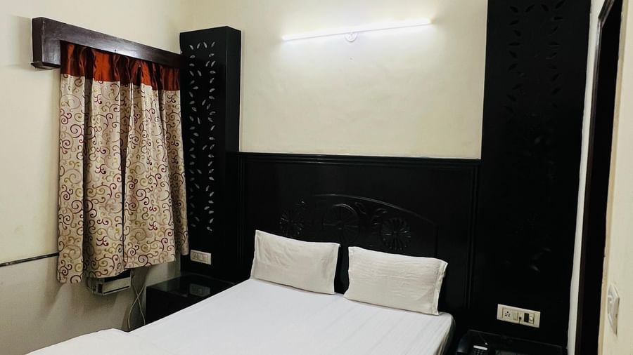 A simple and clean standard room with a comfortable bed, a ceiling fan, and dark wood furniture, offering basic amenities for a restful stay at Hotel City Palace DX.