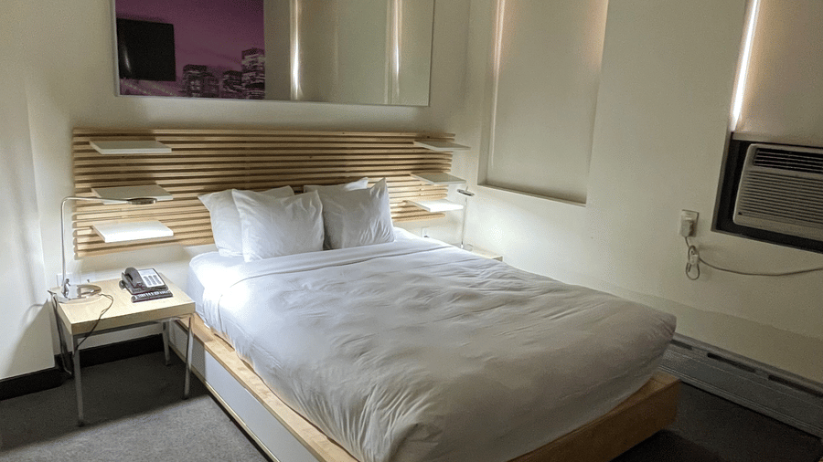 Guest room at Night Hotel Broadway with a bed, side table, and window with daylight.