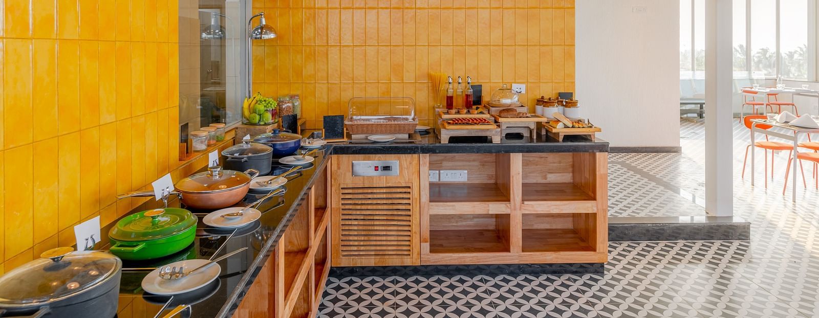 A bright buffet area with vibrant yellow walls and a well-organized food station, inviting guests to indulge in a variety of culinary delights in a cheerful and welcoming environment  at Bedzzz Xclusiv Morjim, Goa