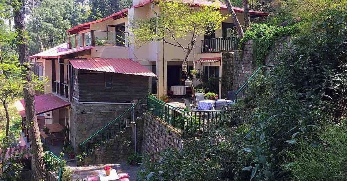 Facade view of SOUTHGATE KASAULI BY ZENQ with bush covering them at the front. 