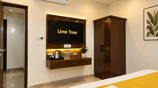 Room with a wall-mounted TV above a tea and coffee station, beside a wardrobe.