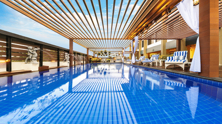an image of a swimming pool with wooden patio at A side view of the lobby with sofa sets at Grand Kakinada by GRT Hotels