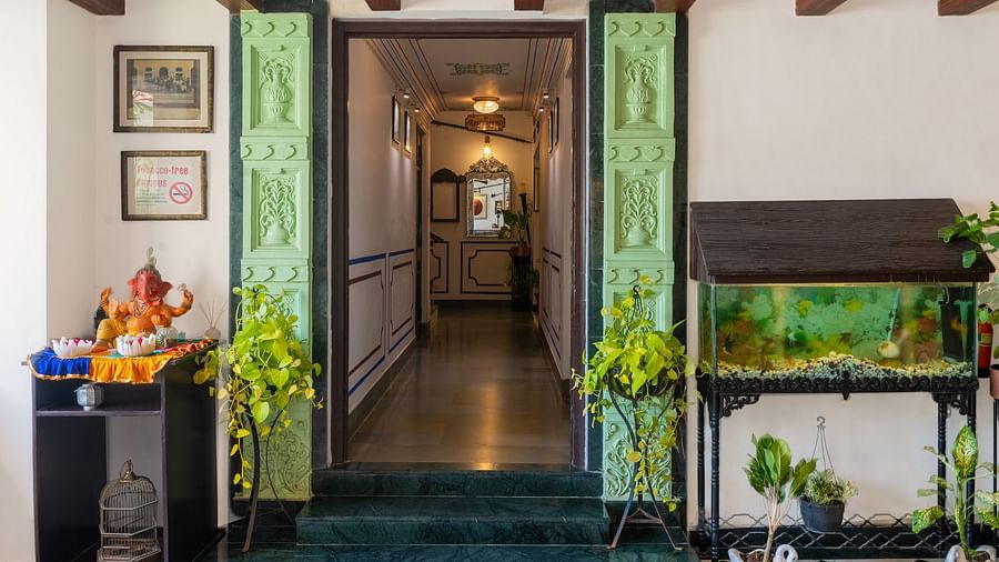 Pathway from the reception area at Panna Vilas Palace features a fish tank with small fish and a statue on a wooden table on the opposite side | Panna Vilas Udaipur