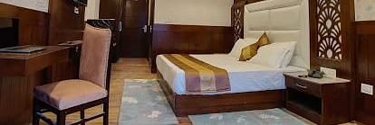 A spacious hotel room with a king size bed, two armchairs, a coffee table, a desk | DLS La Serene Manali