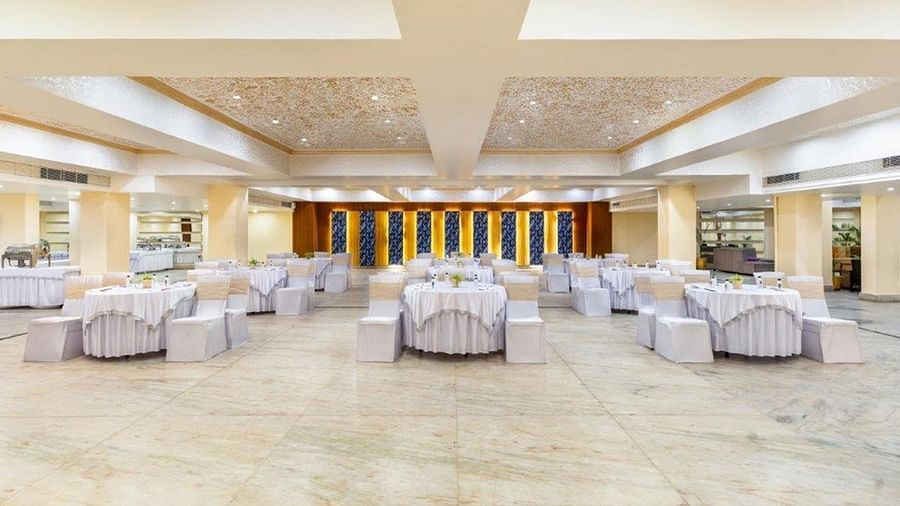 The view of a banquet hall with multiple round tables and chairs at Golden Tulip, Udaipur.