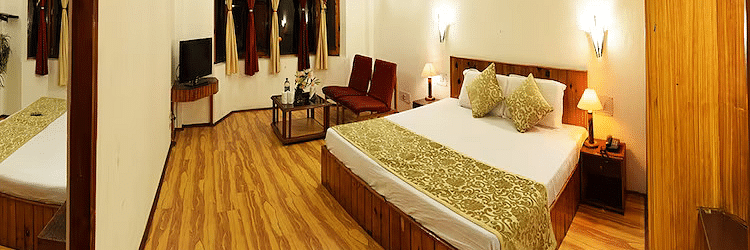 A room at DLS Hotel Devlok, Manali with a double bed, side tables, a wardrobe and wooden flooring